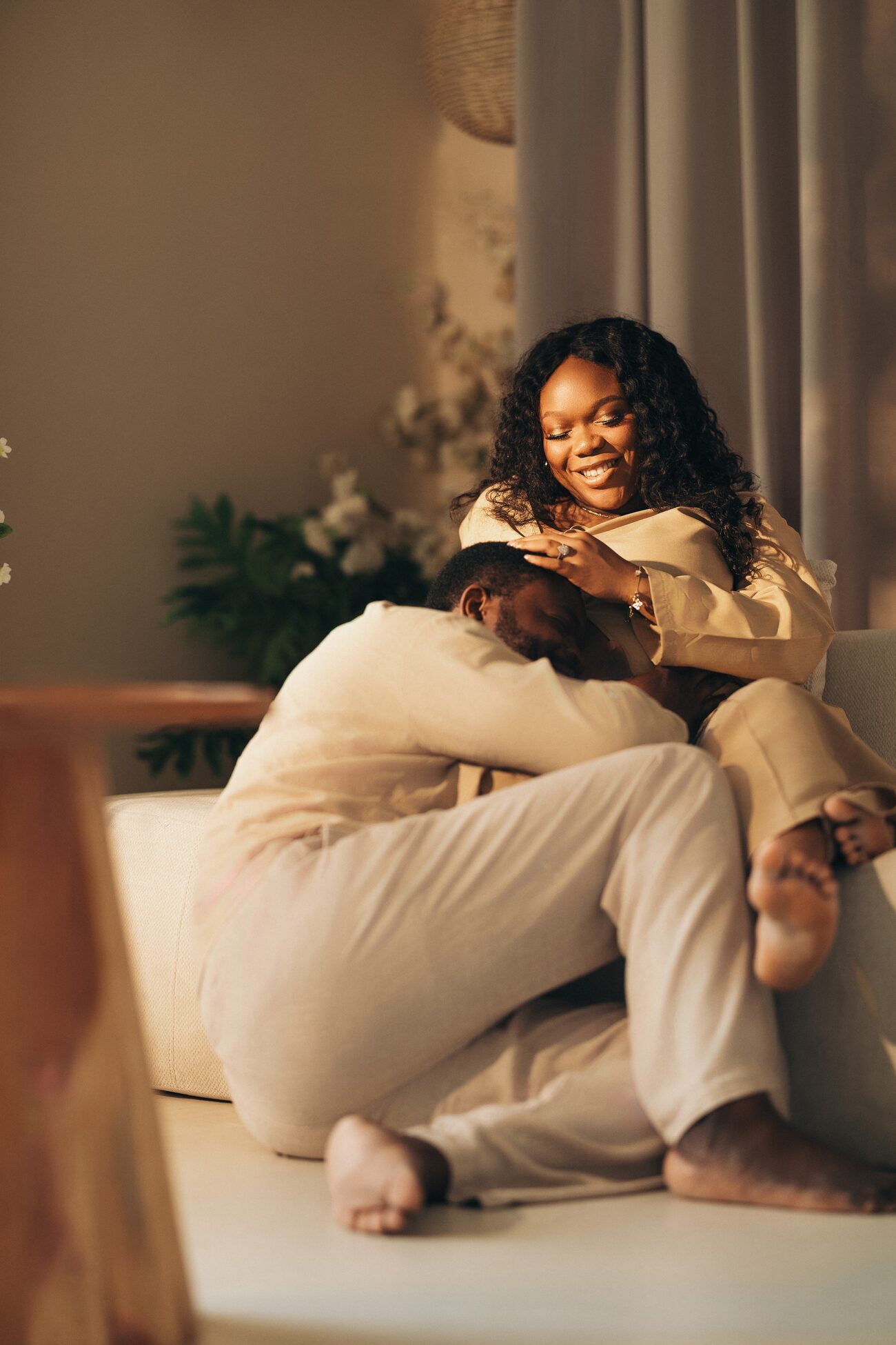 Expectant couple laughing together on a sunlit couch