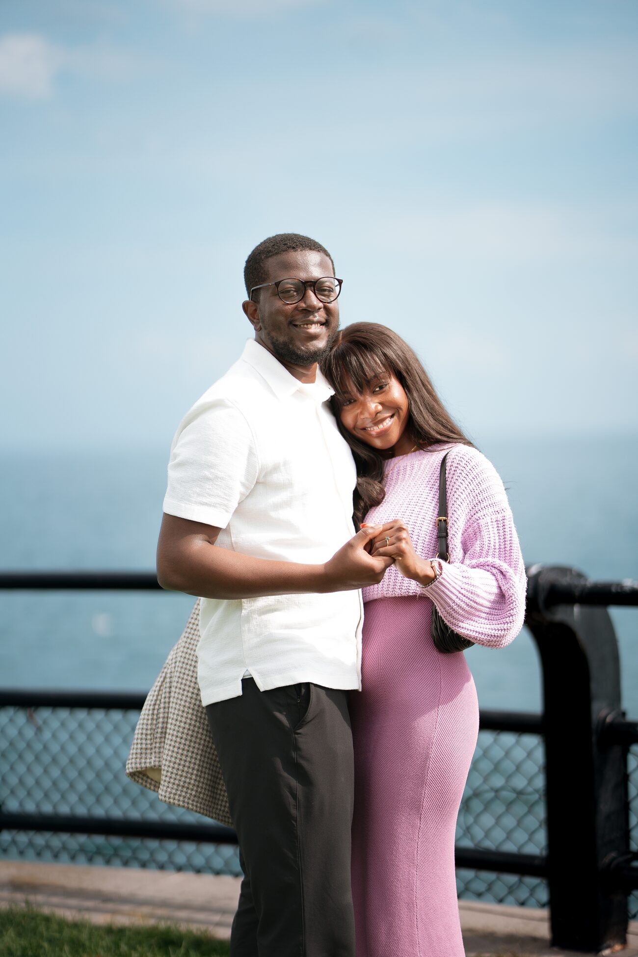 Couple standing close together by a lakeside railing