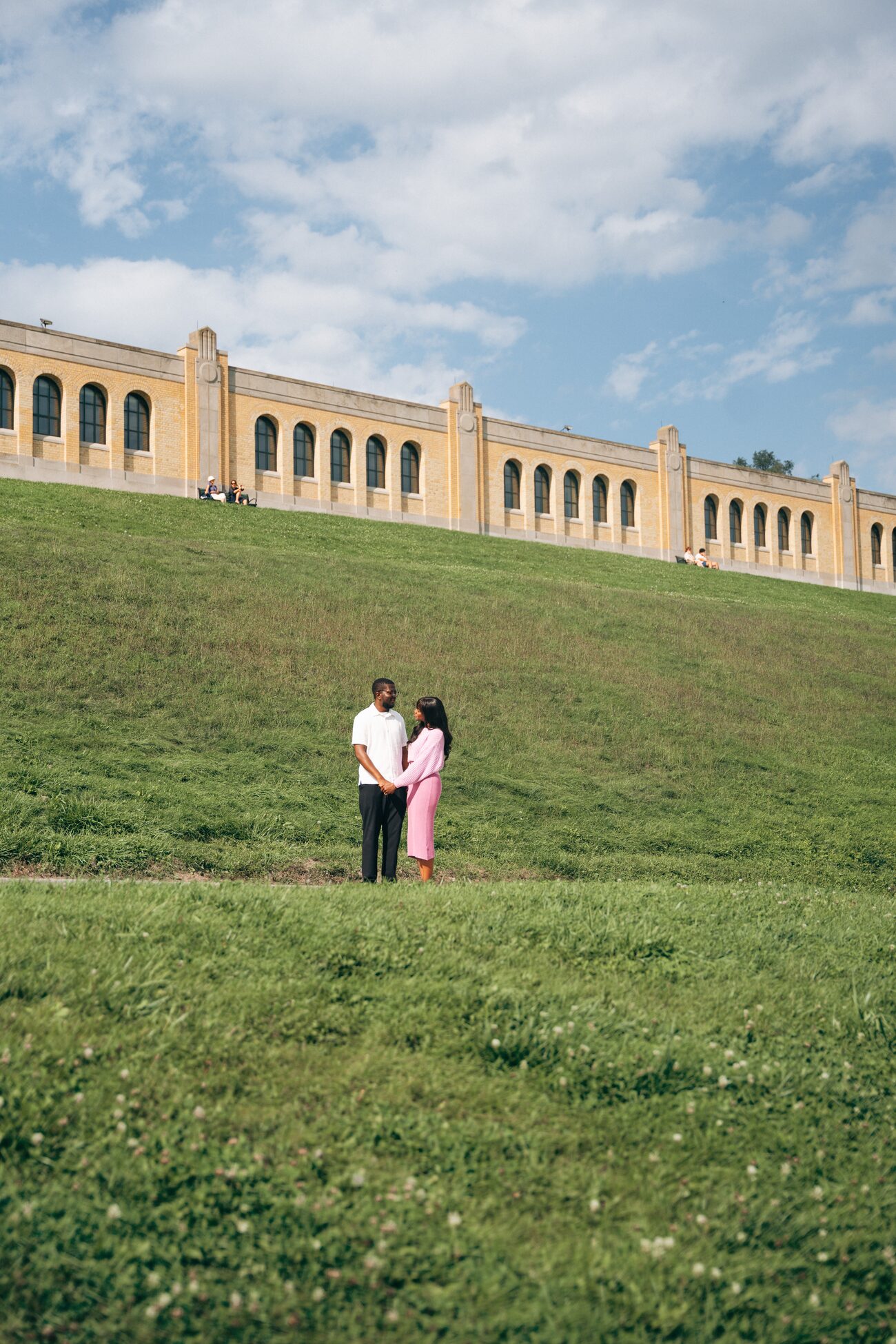 Couple small against a green hill and stone colonnade