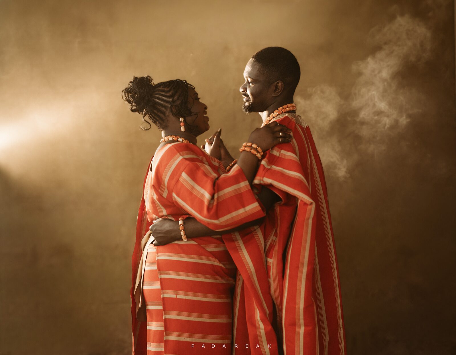 Couple in traditional attire embracing in warm, hazy light