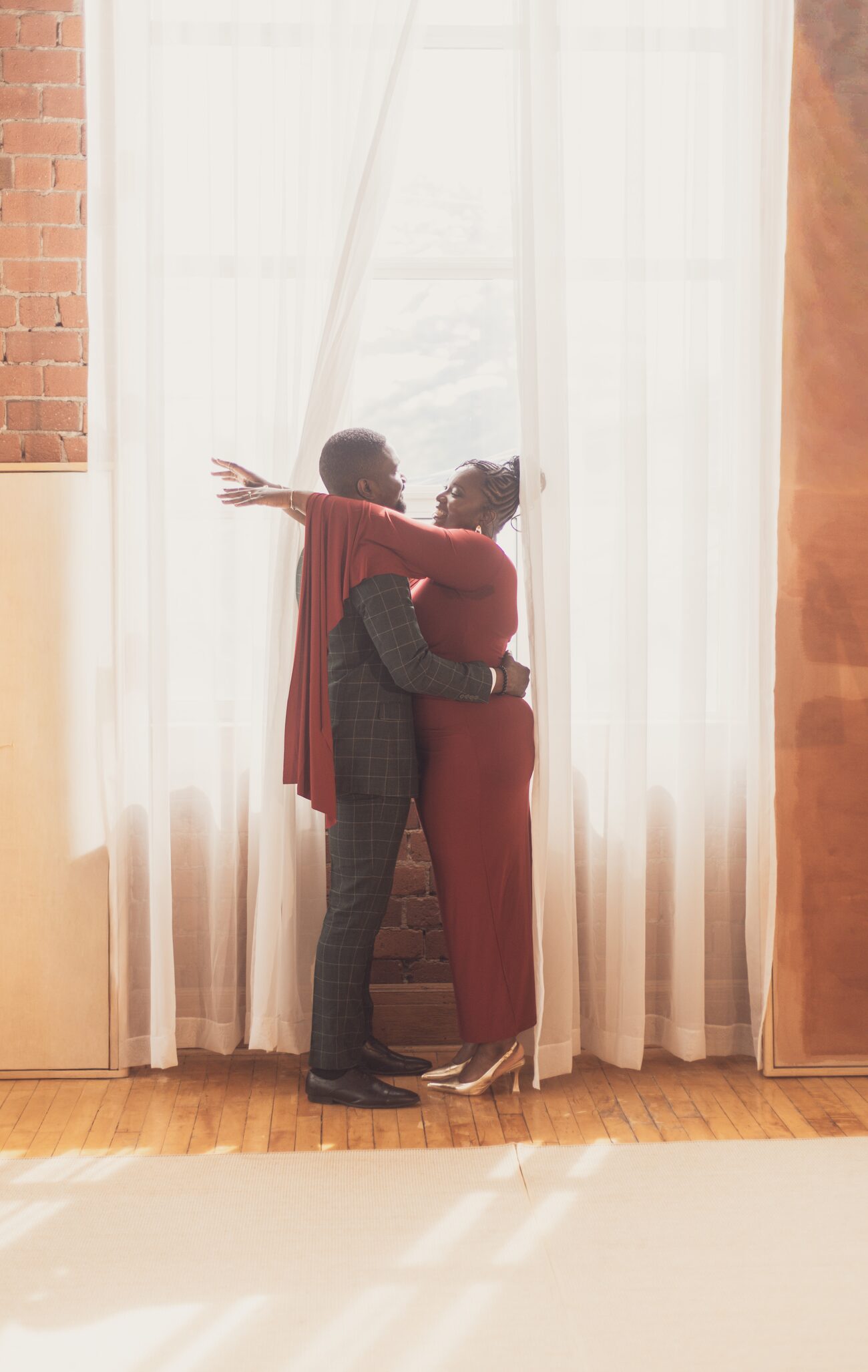 Couple embracing against a sunlit sheer curtain